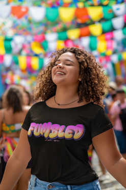 Female wearing a black t-shirt with 'FUMBLED' printed on it, standing in front of colorful flags.