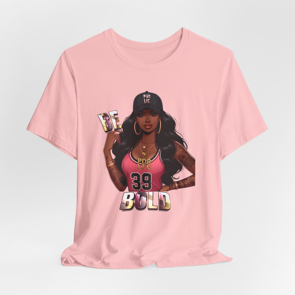 Pink t-shirt with a graphic of a woman and 'Be Bold' text on a light gray background