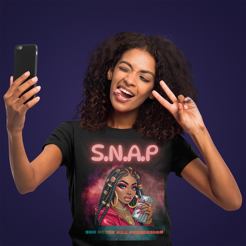 Woman wearing a t-shirt with a graphic design and text, taking a selfie against a dark background.