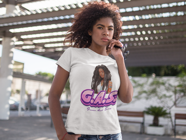 Woman wearing a white G.A.S. T-shirt with a graphic design and text, standing outdoors.